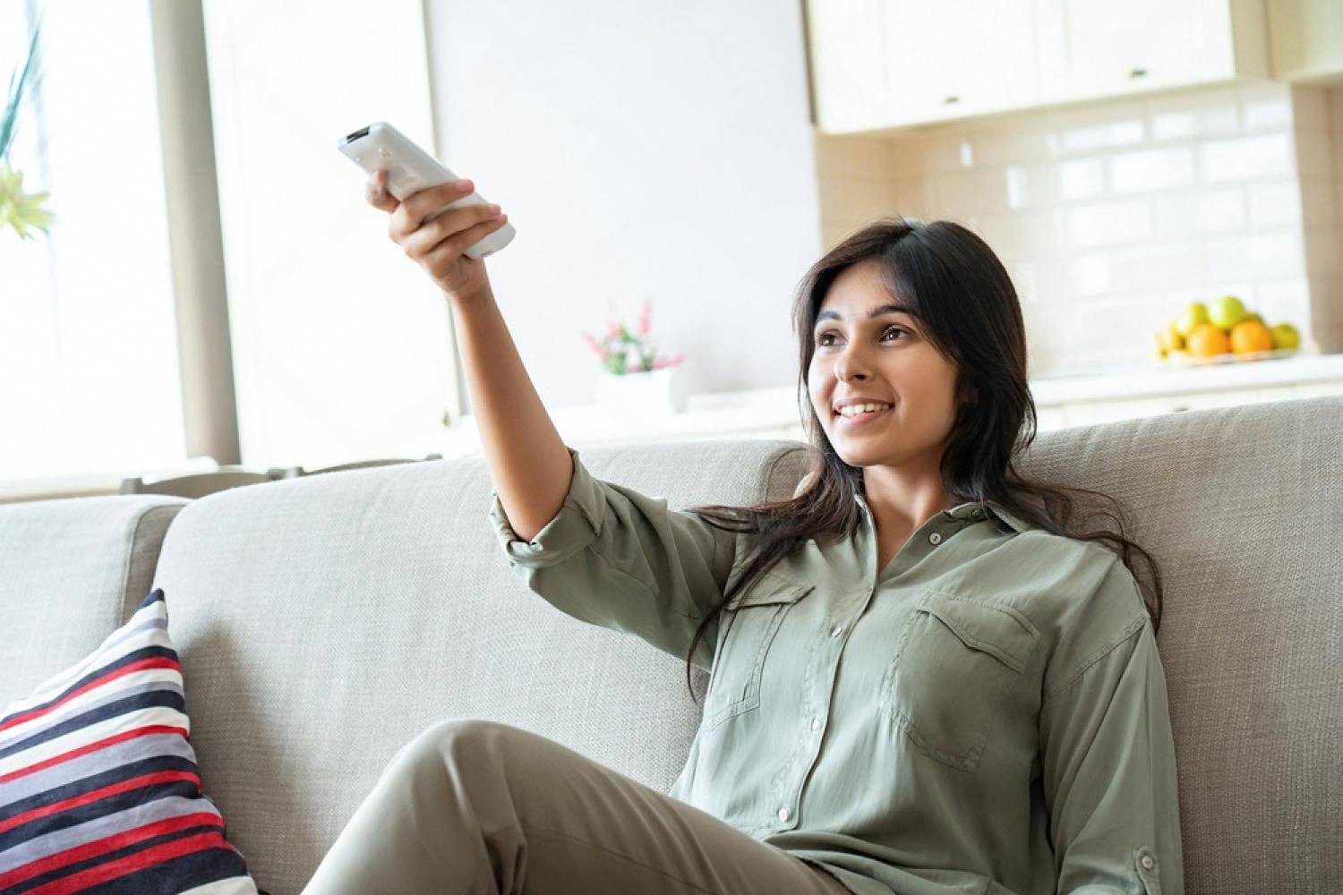 Woman relaxing on a sofa in a cool, well-shaded UAE living room during summer