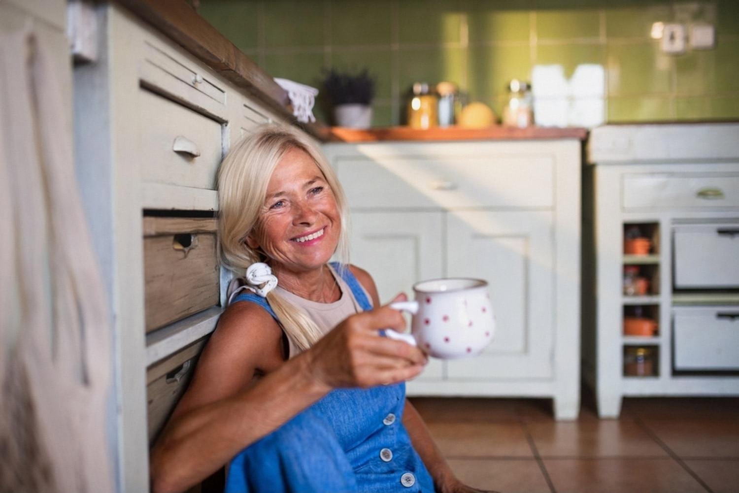 Woman enjoying morning coffee in a bright kitchen with sunlight streaming through the window